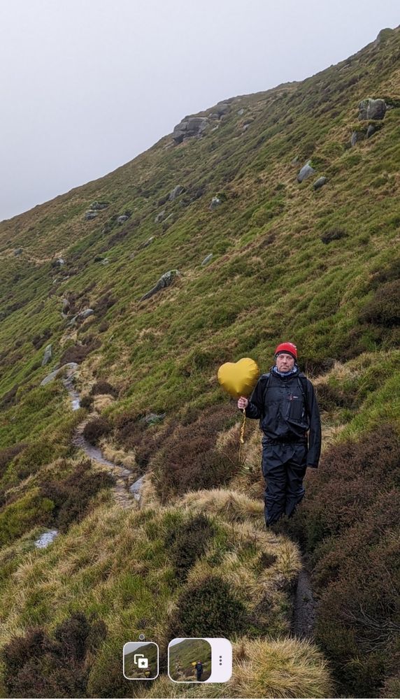 A deceptively handsome man holding a helium balloon heart.