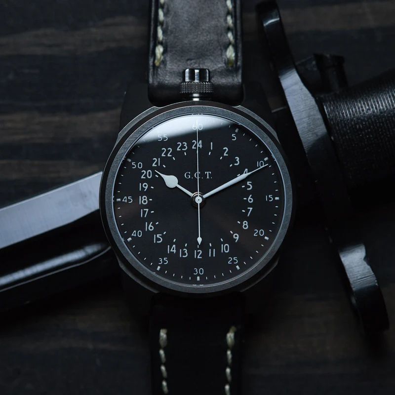 A wristwatch with a black dial and white hands 