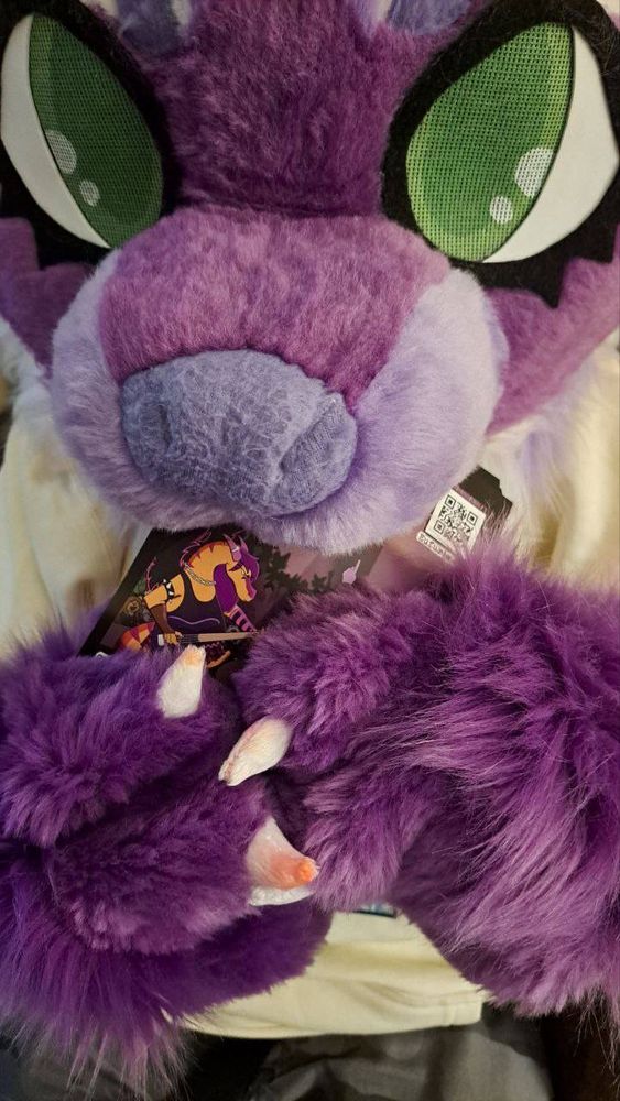 Extreme closeup of Joy the purple raccoon eating a Eufuria 2026 flyer.