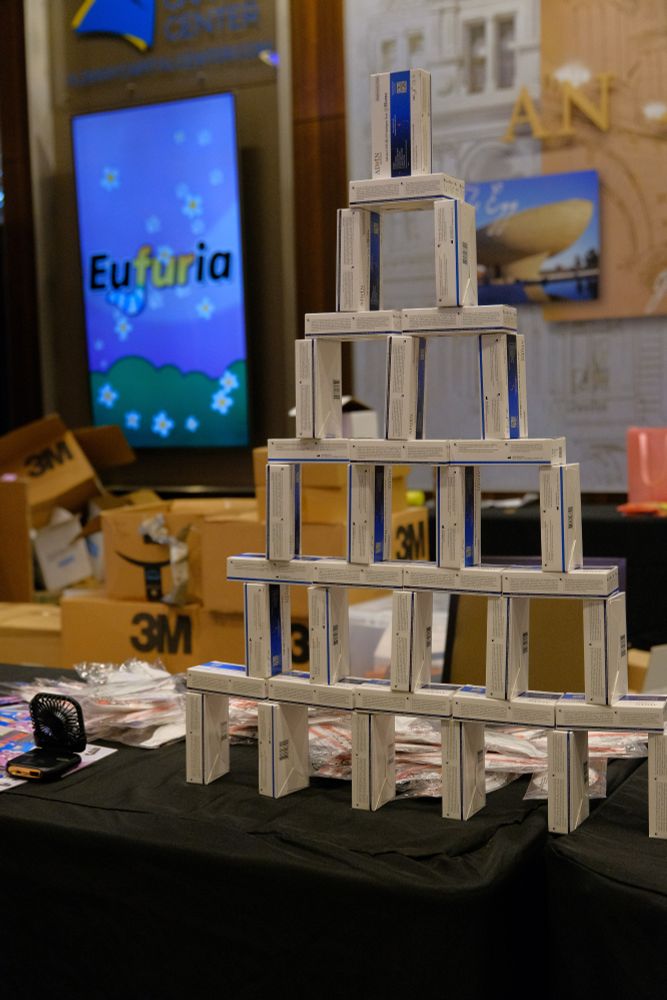 A pyramid of stacked Covid-19 test boxes on the registration desk at Eufuria, along with packaged Aura masks. In the background is the Eufuria sign.