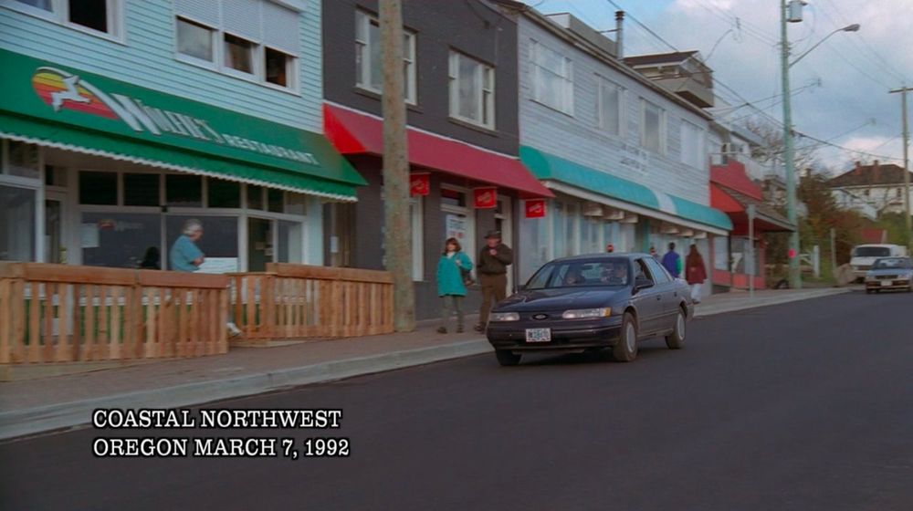 A car on a small town street with the caption, "Coastal Northwest, Oregon, March 7, 1992." 