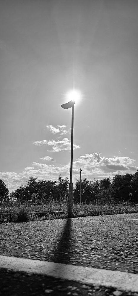 A black and white photo of sunlight and the shadow cast by a light.