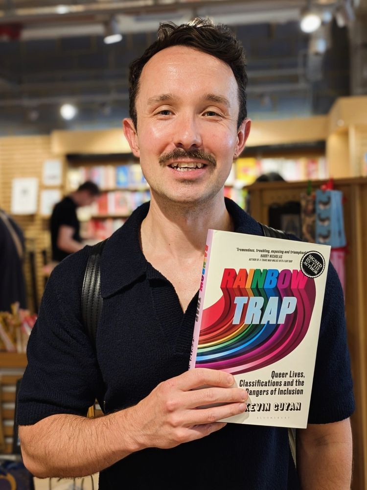 Kevin looking sweaty holding a copy of his book Rainbow Trap in a bookshop in Bloomsbury, London.