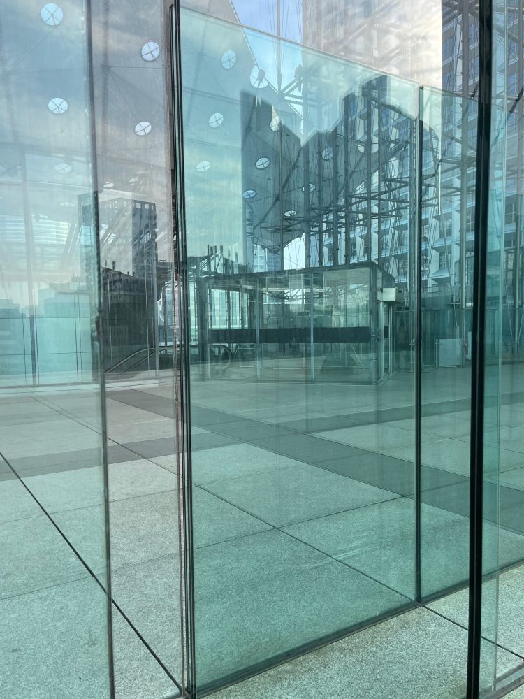 the modern architecture of paris is reflected in slightly turquoise-tinted glass walls; reflection and transparency are difficult to distinguish on this sunny day