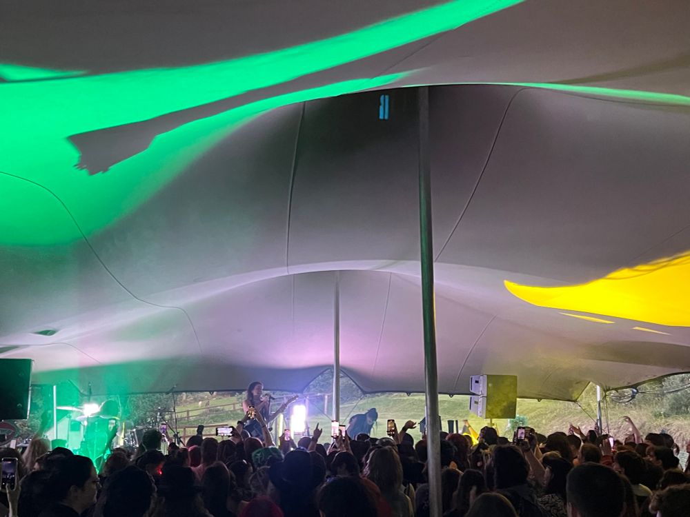 beth mcgarthy playing a live gig in a tent; the ceiling is lit up in green and yellow 