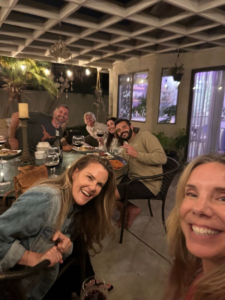 A group of 6 people in a back patio with wine and smiling