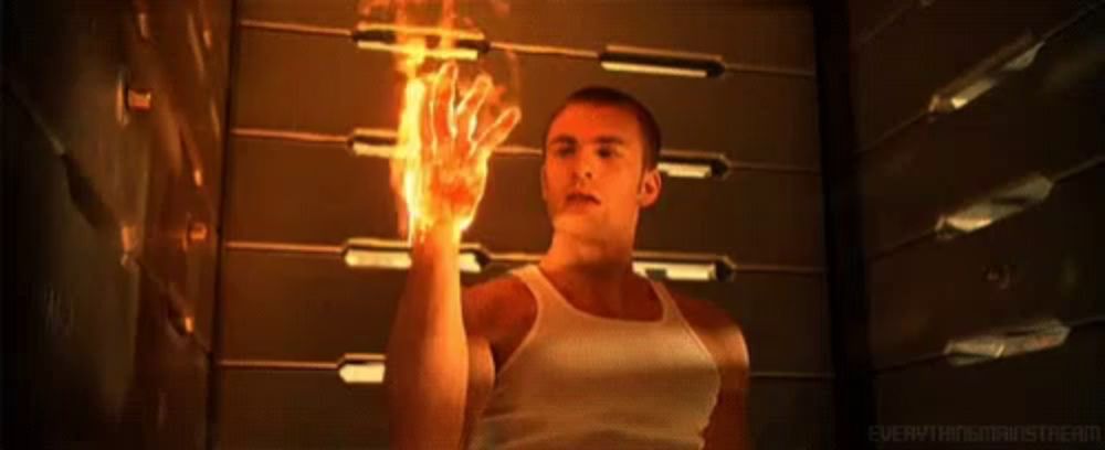 a man in a white tank top is holding a flaming hand .