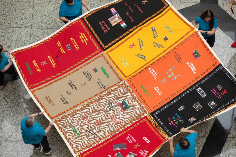 people holding an aids quilt