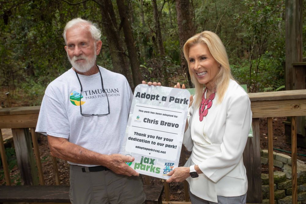 mayor deegan and chris bravo holding an adopt a park sign with his name on it