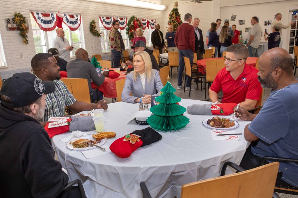 Mayor Deegan sits and talks with others around a table during a holiday-themed meal.
