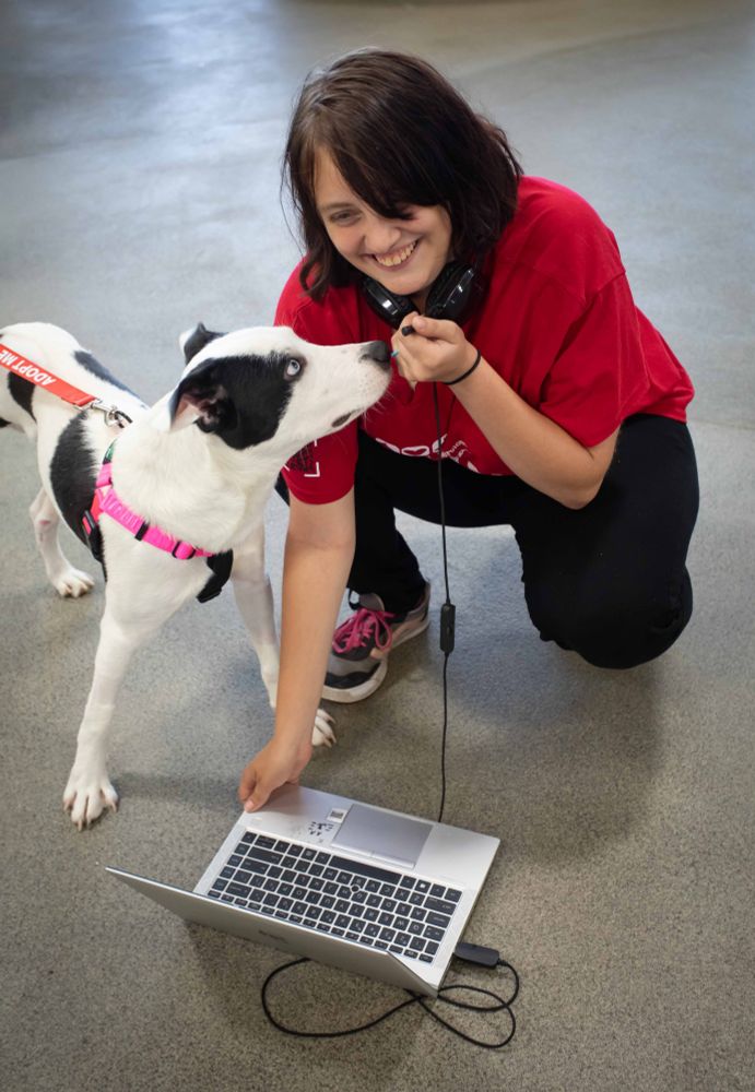 a person smiling at a white and black dog
