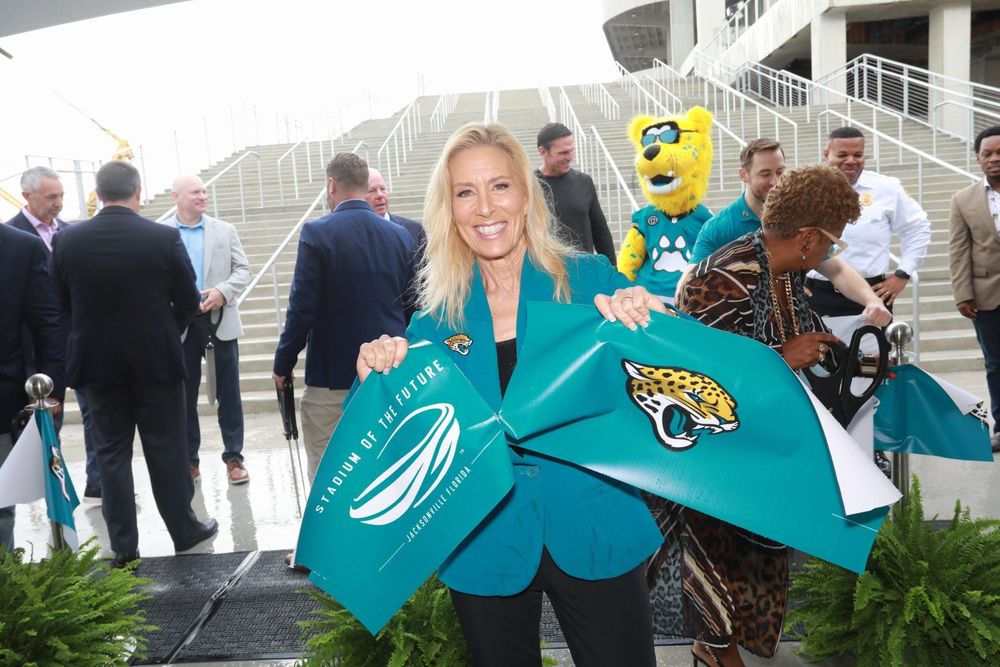 mayor deegan holding two pieces of a teal ribbon