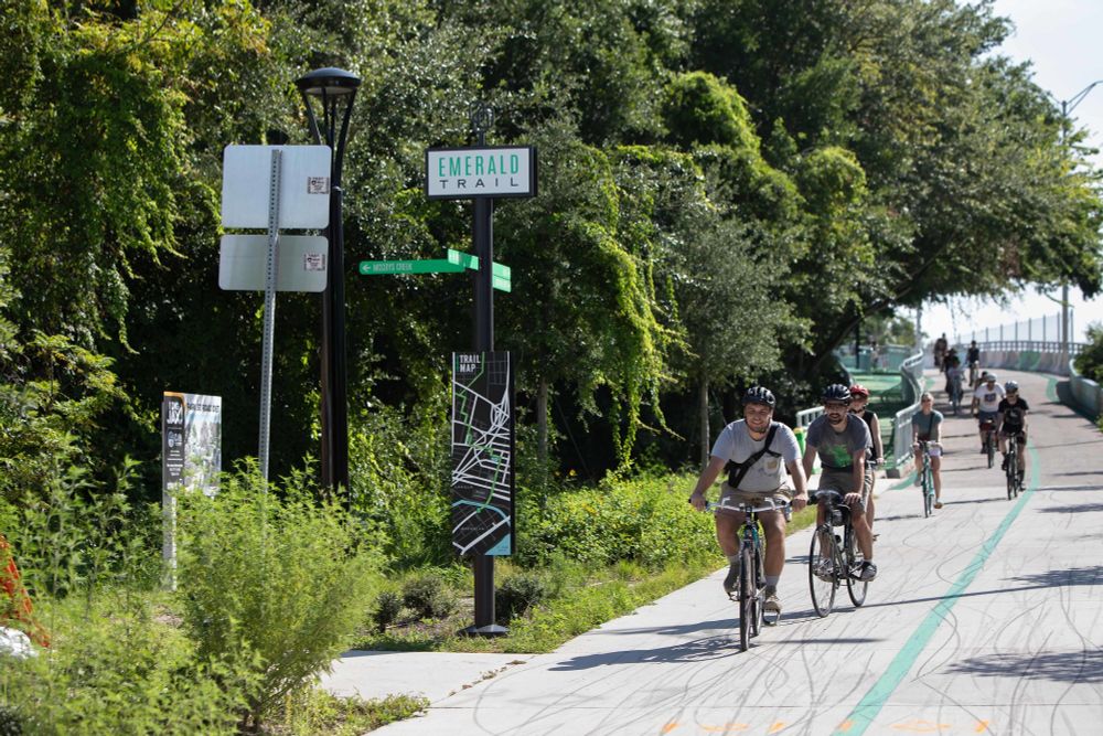 photo shows a group of bicyclists going down the emerald trail next to park street