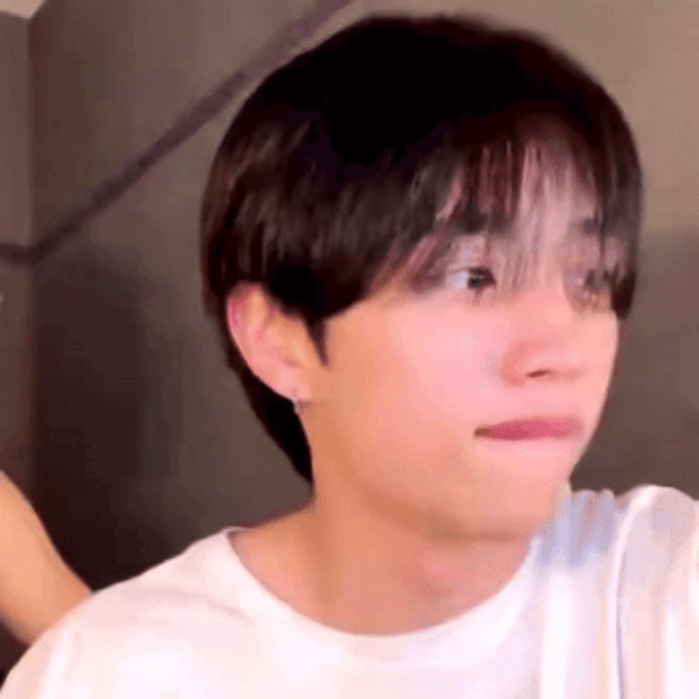 a close up of a young man making a funny face while wearing a white shirt .