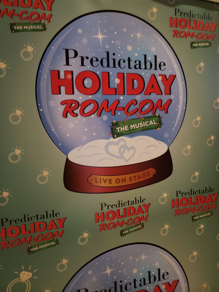 Poster for Predictable Holiday Rom-Com The Musical with the title in a snow globe, with two little hearts etched in the snow on the bottom, and "Live on Stage" on a plaque on the base.