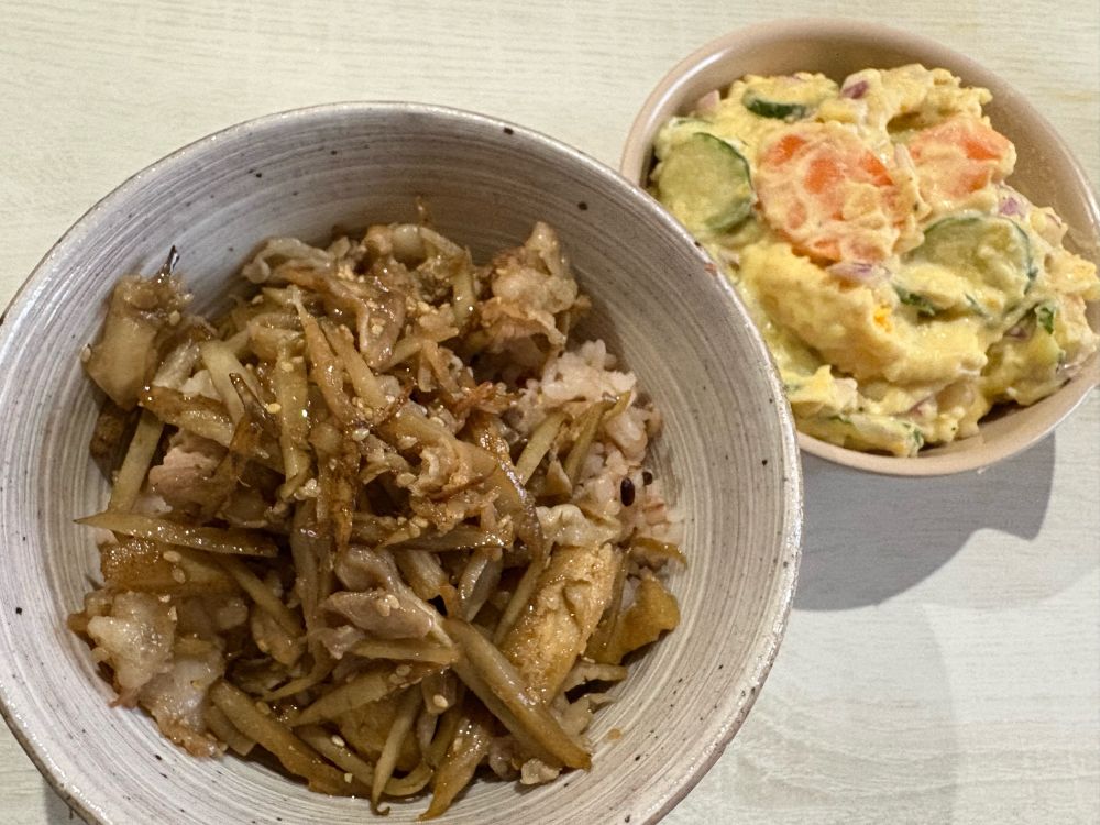 左、どんぶりに豚バラとゴボウと薄揚げとマイタケ炒めたのが乗っかった丼
右にこんもりとしたポテサラ、具はにんじんときゅうりと紫キャベツで定番