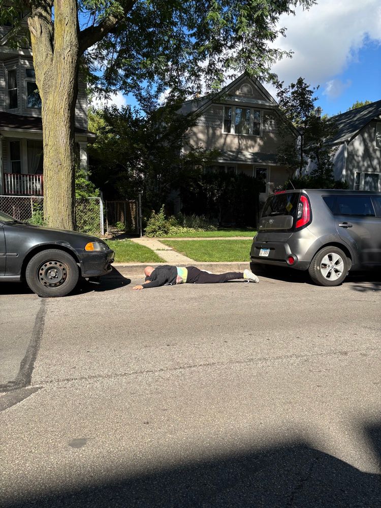 toby lying prone between two parallel parked cars