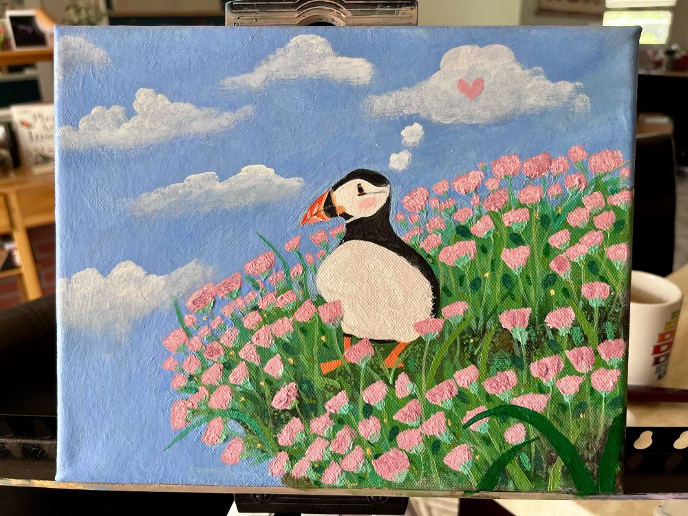 oil painting of a black and white puffin bird standing on a cliff covered in pink flowers and green foliage in front of a cloudy sky. the puffin appears to be day dreaming about love and blushing. 