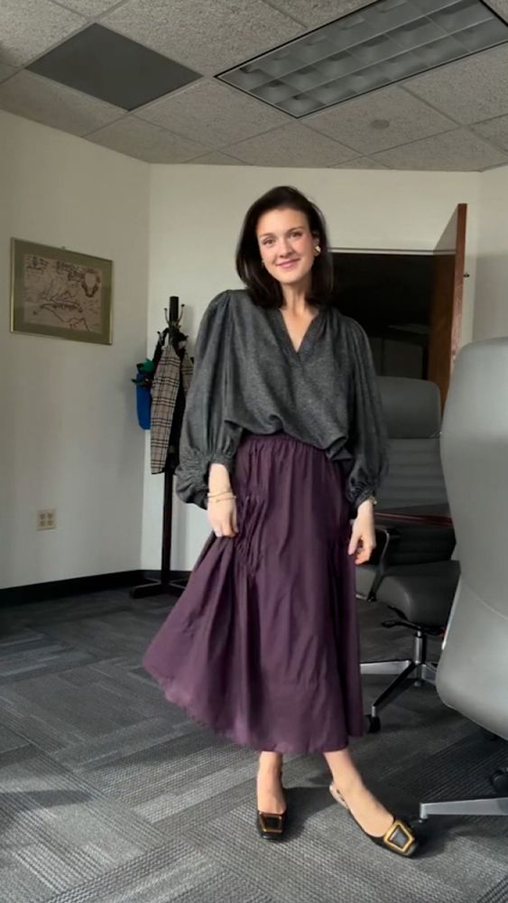 A very ugly outfit with a black blouse and purple tiered maxi skirt and hideous pilgrim shoes