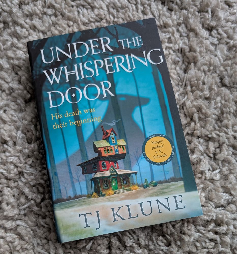 Under the Whispering door by T J Klune lying on rug
