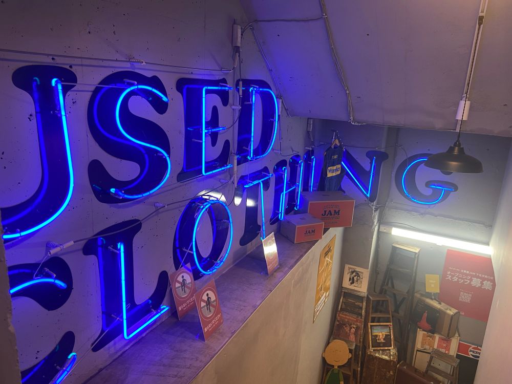 A neon sign leading to a vintage clothing shop underground