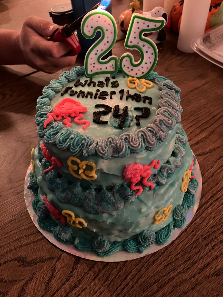 SpongeBob themed cake with flowers and jellyfish. It says “What funnier than 24?” With candles that are a 2 and a 5 for 25. 