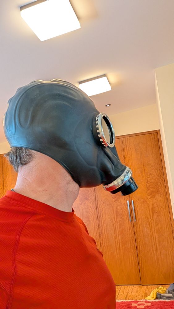 Side view of a person in a red shirt wearing a Russian style gasmask 