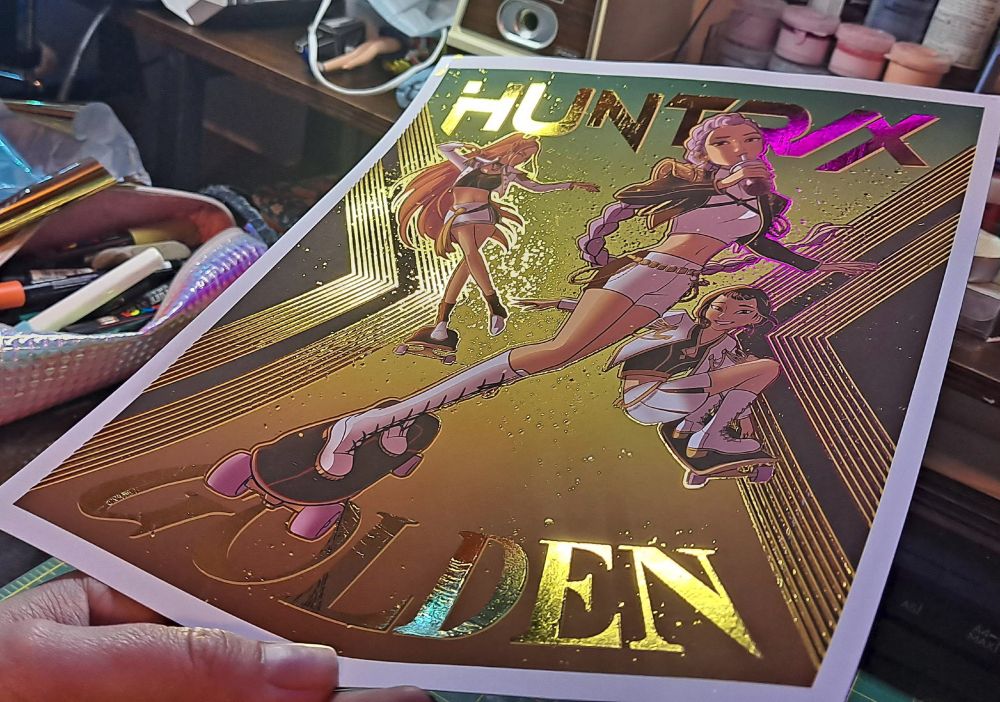 Gold foiled art of HUNTRIX (Rumi, Zoey, and Mira) from Kpop Demon Hunters, skating and drinking boba!