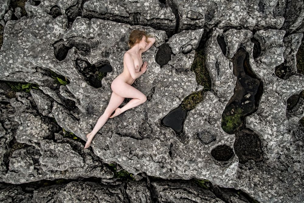 Nude woman lying on limestone pavement