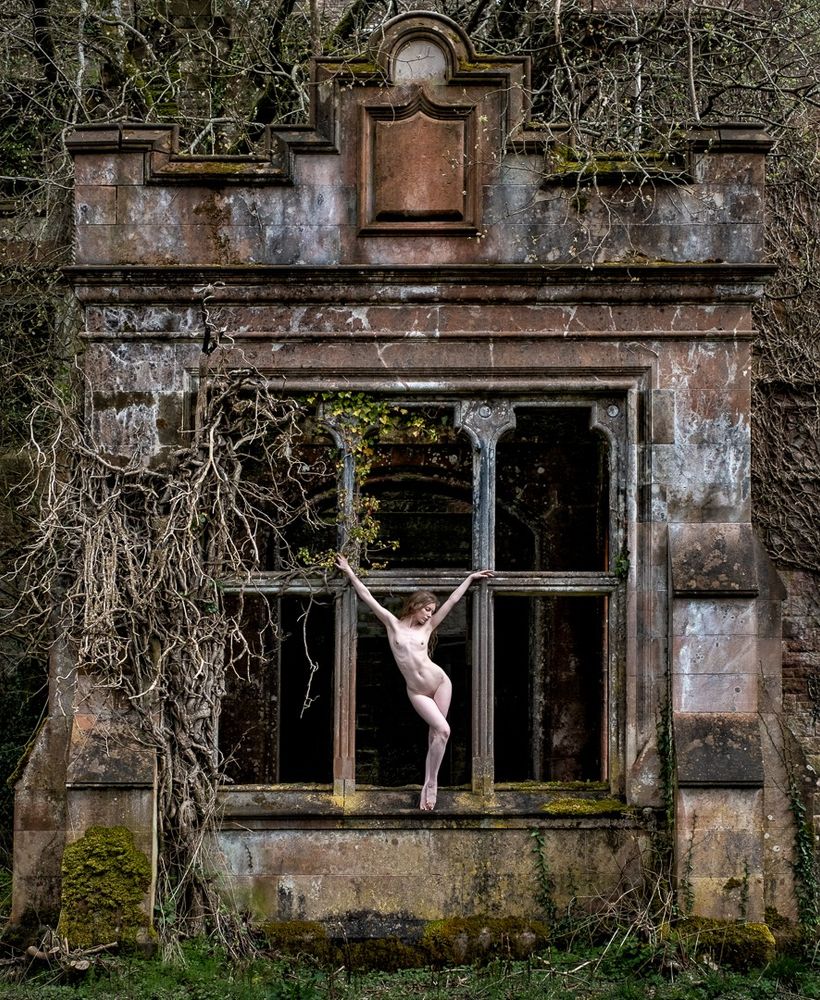 Nude woman standing in window of derelict building