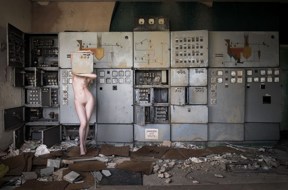 nude women in control room holding panel over face.