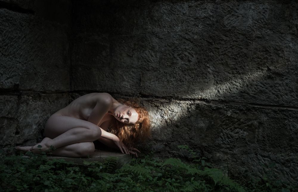 Nude woman lying in beam of light,