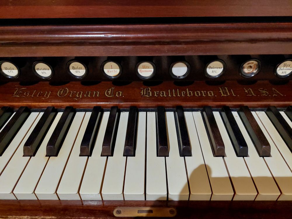 Keys and stoppers on an old pedal organ, with maker's logo saying "Estey Organ Co. Brattleboro, Vt, U.S.A"