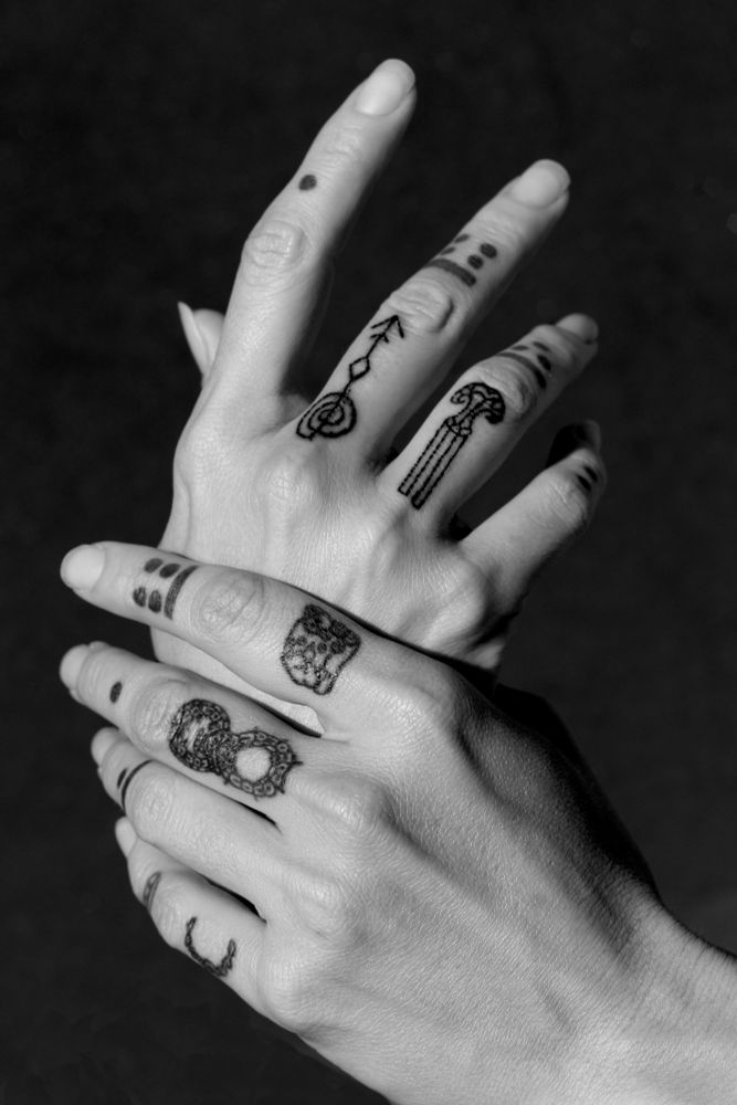 Black and white photo of tattooed fingers grasping hands