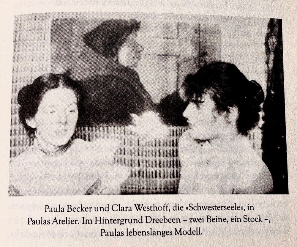 Zwei Frauen im Gespräch: links das Porträt, en face von Paula und rechts das Porträt von Clara im Profil , im Hintergrund ist eine Malerei ebenfalls im Porträt, Profildarstellung zu sehen, s/w Foto 