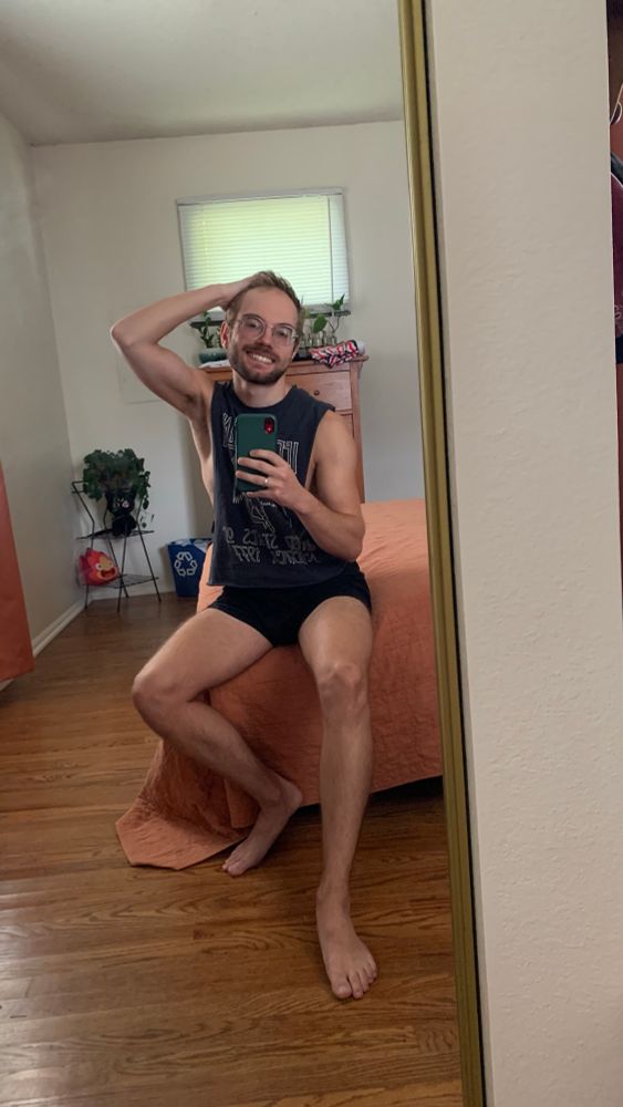 reflection of man in black boxers shorts and led zeppelin tank top sitting on a bed