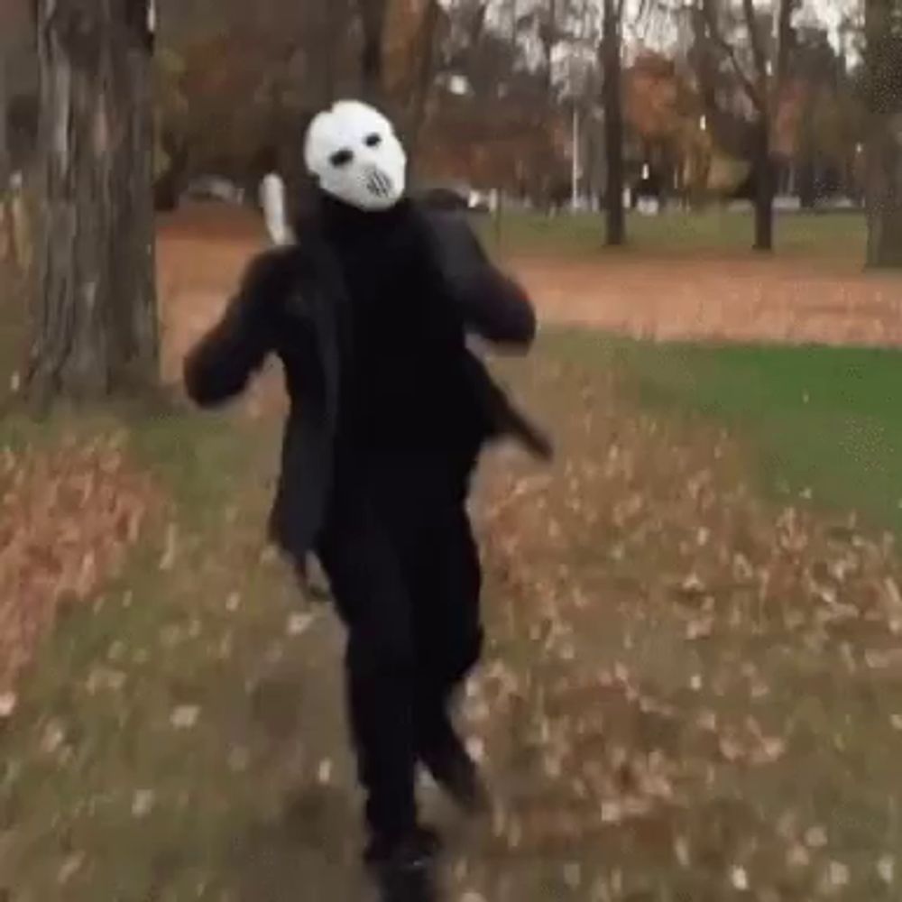 a person in a mask is running in a park holding a gun .