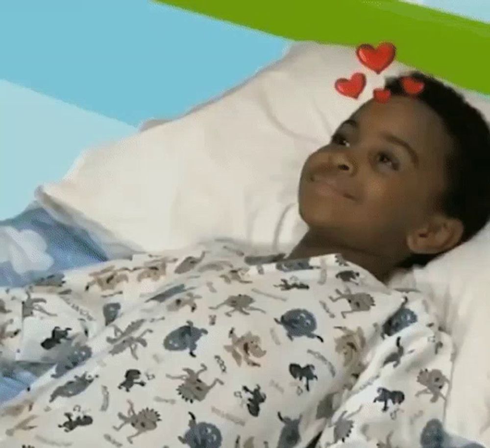 a young boy is laying in a hospital bed with hearts on his head