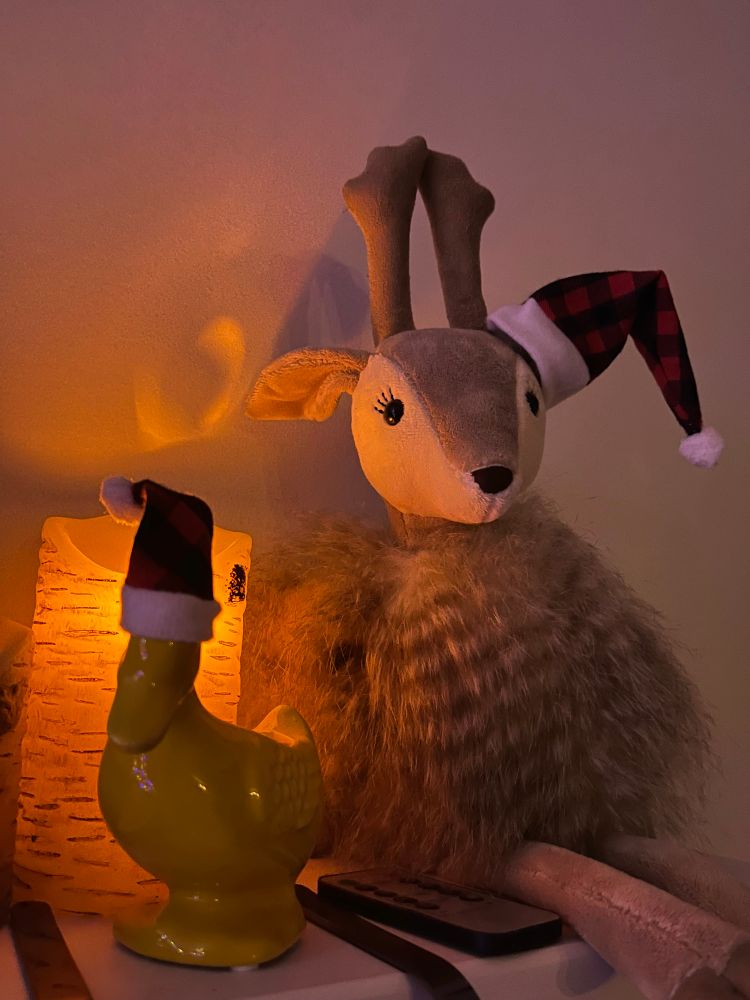 Stuffed deer and ceramic duck in Santa hats