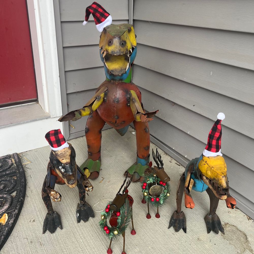 Metal dinosaur lawn statues wearing Santa hats