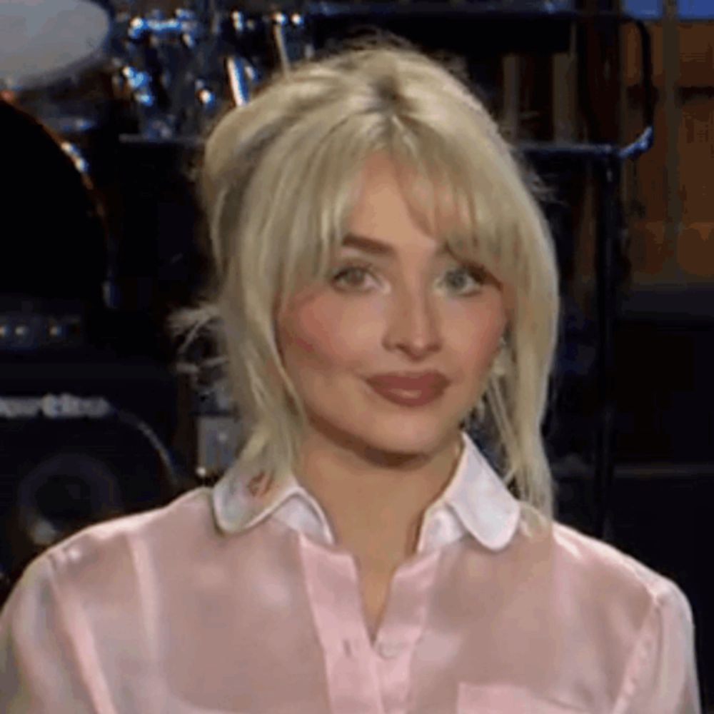 a close up of a woman wearing a pink shirt and a white collar .