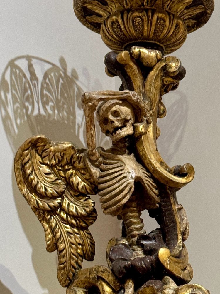 18th century funeral torch detail of a gold-played, winged skeleton 