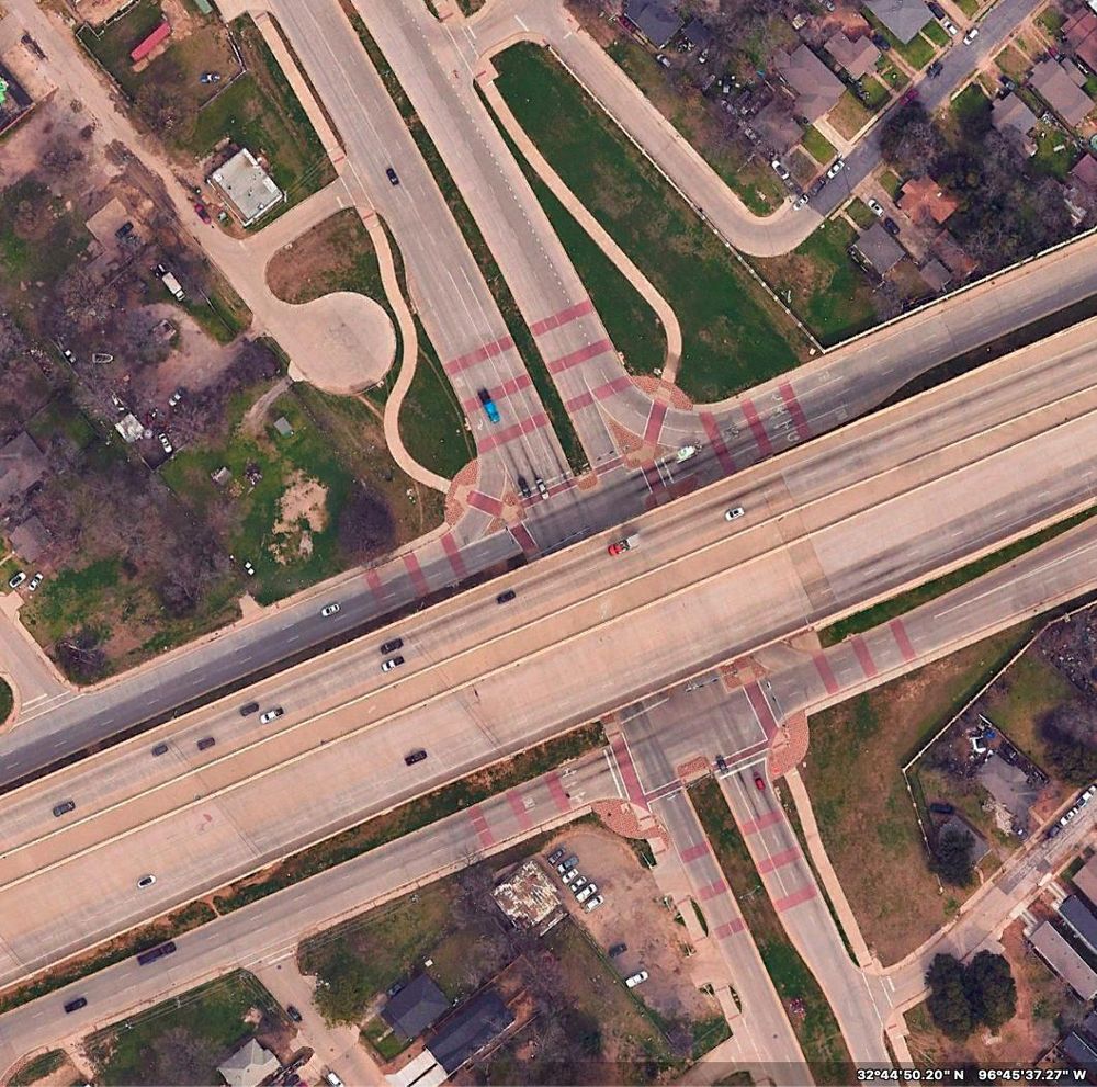 A 2023 aerial photo of the same interchange. Now S M Wright Freeway has been turned into an at-grade "boulevard" (but 175 is now an elevated freeway, and has been extended west.) Also visible are the shared-use paths on either side of Wright for walking and rolling. Nice. And an interesting visual treatment of the intersection, with red bands added to the road surface.