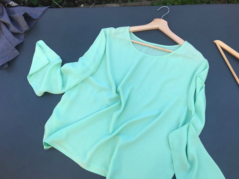 Le top sur une table pour souligner le drapé et la finesse du tissu.