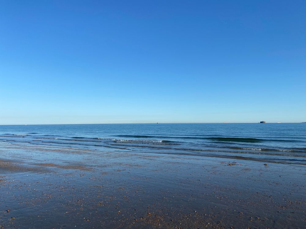 Beach in the foreground. Sea in the background. Blue sky.