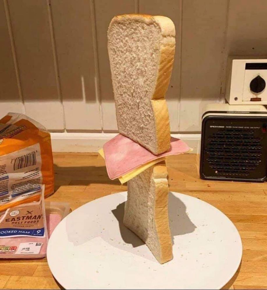 Picture of two slices of bread, one stacked on top of the other crust side, with ham and cheese in between 