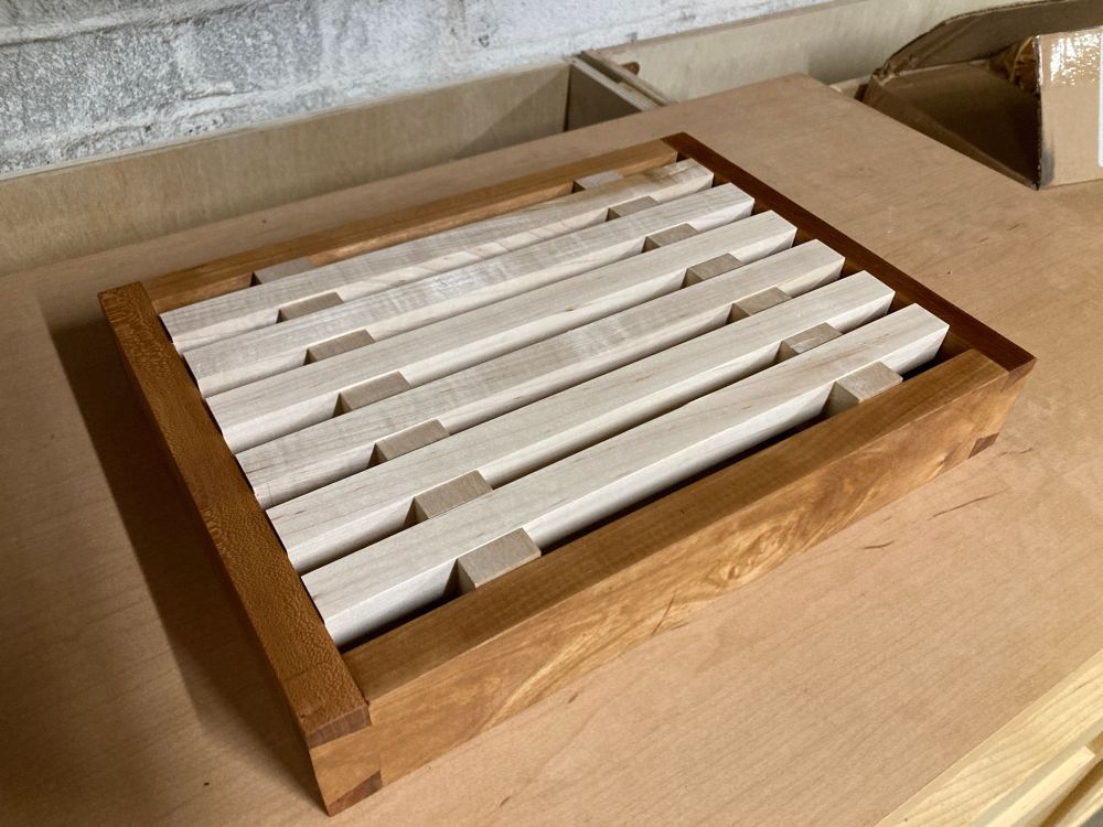 a crumb catching cutting board for cutting bread, made out of cherry, maple, and poplar.