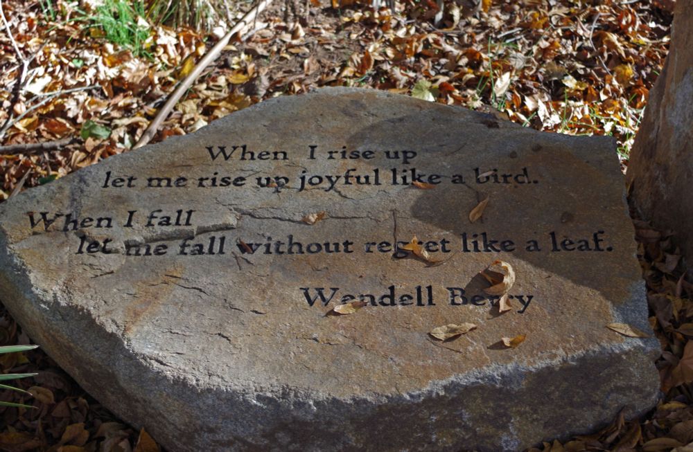a flat rock with this inscribed on it: When I rise up let me rise up joyful like a bird. When I fall let me fall without regret like leaf. Wendell Berry