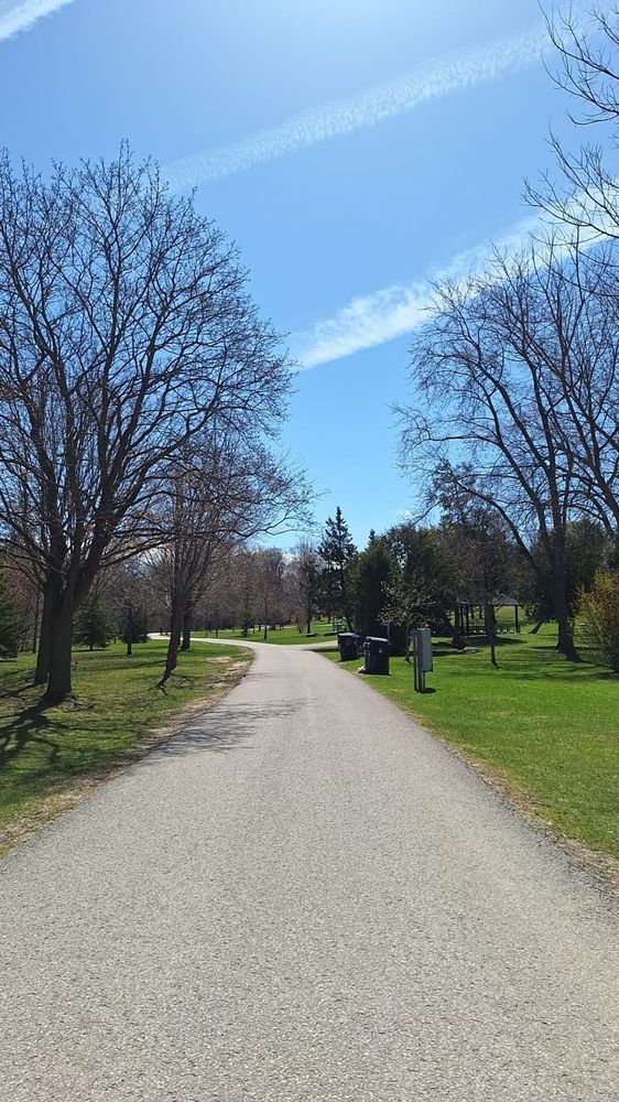 The picture I took shows a straight road that bends after some distance. It's surrounded by greenery and blue sky.