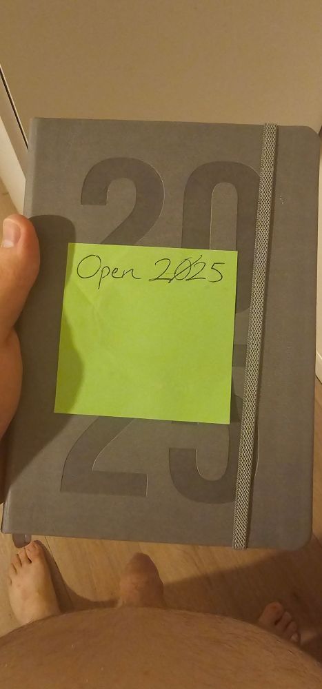 A perspective photo of me looking down at a 2025 desk diary with a green sticky note saying "open 2025".